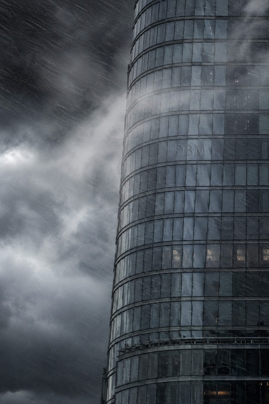 Rain-lashed glass facade of a coastal tower during a storm