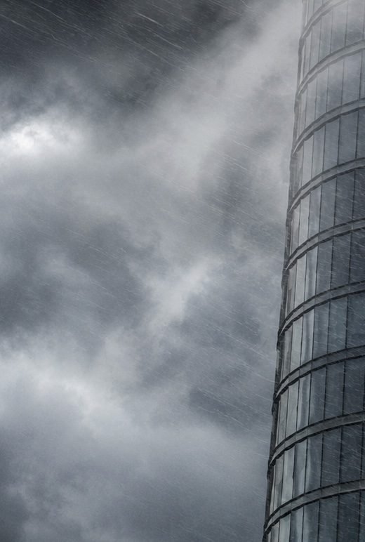 A glass residential tower under a darkening storm sky